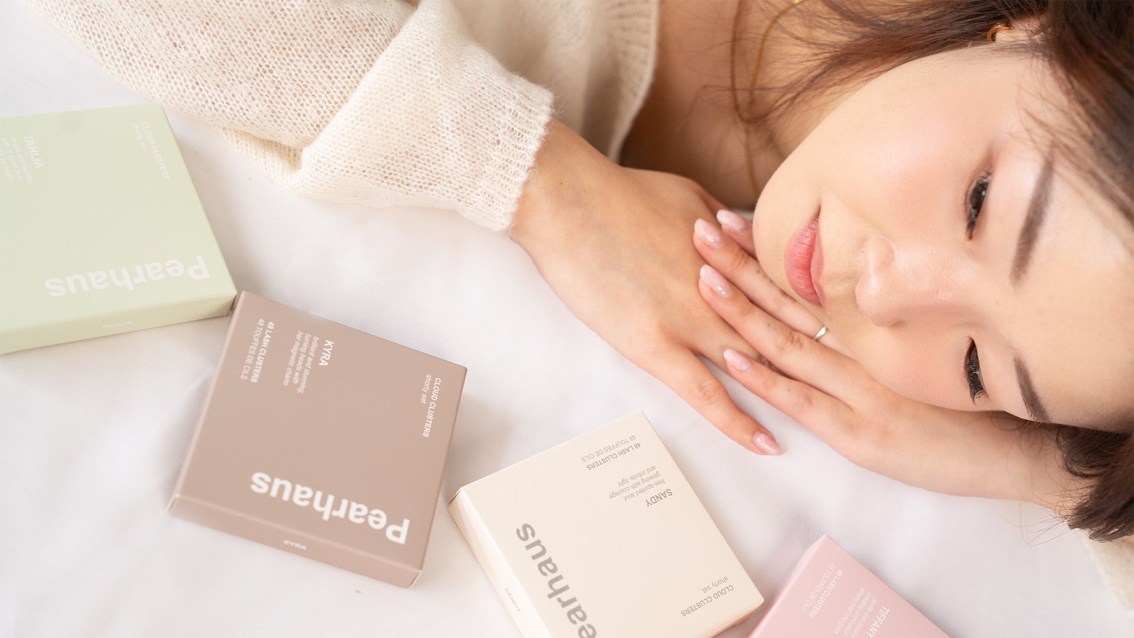 Pearhaus model wearing lashes beside Cloud Cluster boxes